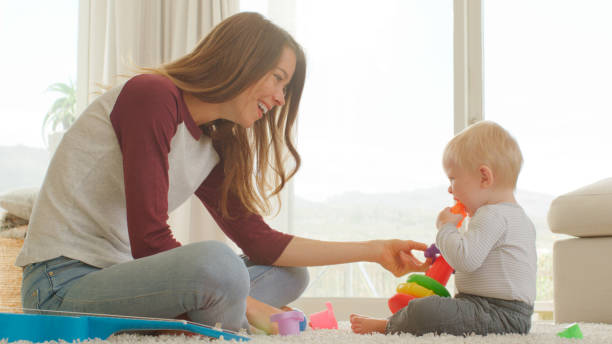 istock Mother Sits With Baby Son At Home Playing With Plastic Stacking Toys 2200801054