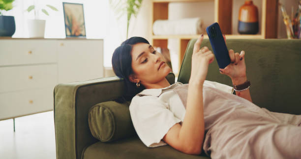 istock Relax, phone and scroll with woman on sofa for streaming, social media and networking app. Connection, online news and internet with person in living room at home for mobile, web and communication 2200801320