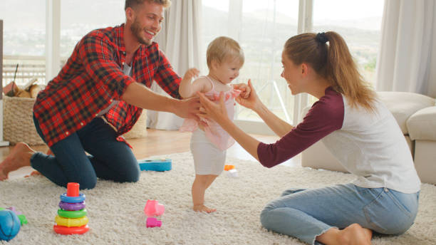 istock Parents Helping Baby Daughter To Take First Steps At Home 2200801748