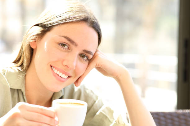 istock Happy young woman drinking coffee looking at you 2200802107