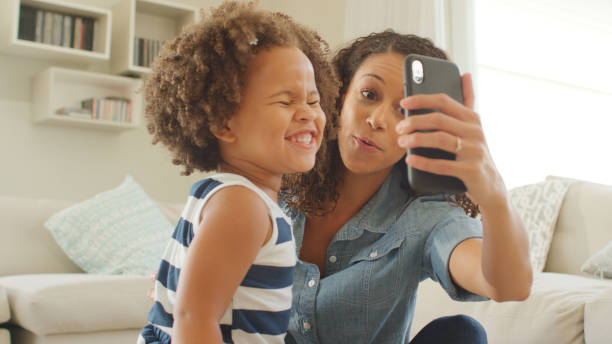 istock Mother Sits With Daughter At Home Taking Selfie On Mobile Phone 2200802313