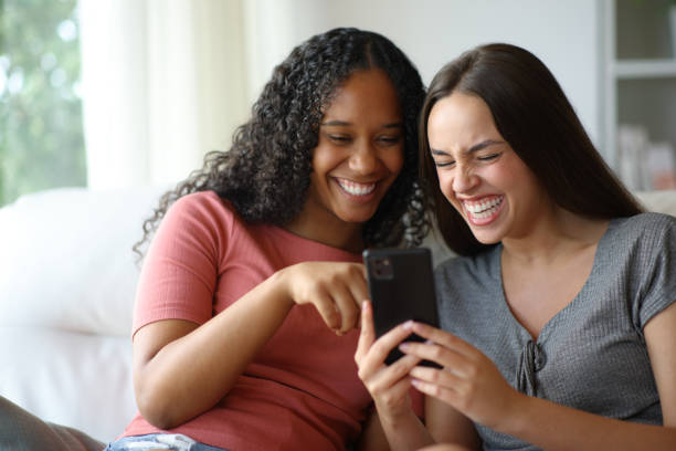 istock Happy interracial friends laughing hilariously checking phone 2200802603