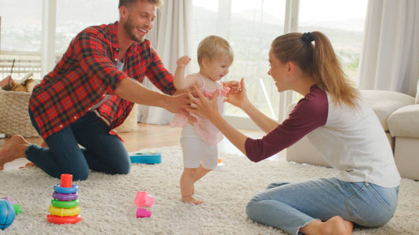 istock Parents Helping Baby Daughter To Take First Steps At Home 2200802657