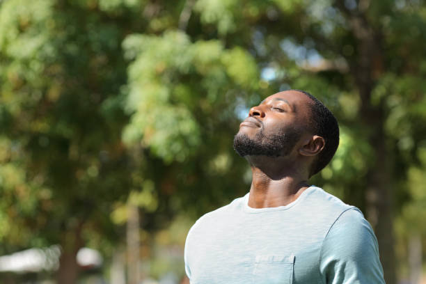 Black man breathing fresh air on green park stock photo