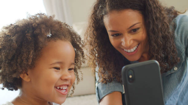istock Mother Sits With Daughter At Home Taking Selfie On Mobile Phone 2200802840