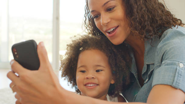 istock Mother Sits With Daughter At Home Taking Selfie On Mobile Phone 2200803459