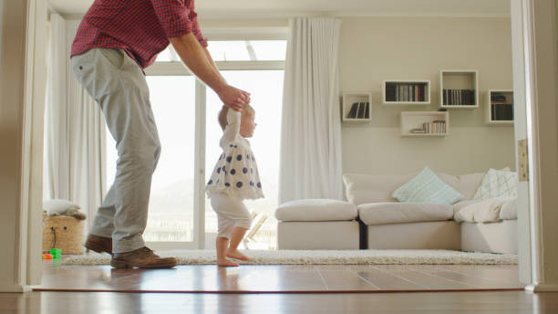 istock Father Helping Baby Daughter To Take First Steps At Home 2200803907