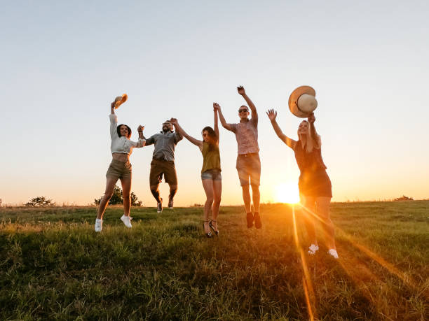 istock Group Of Friends Jumping In The Field At Sunset 2200805110
