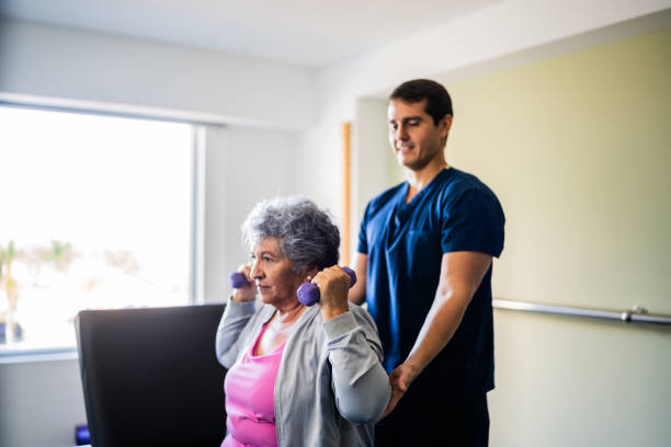 istock Mid adult physical therapist helping patient during exercise with dumbbell 2200807475