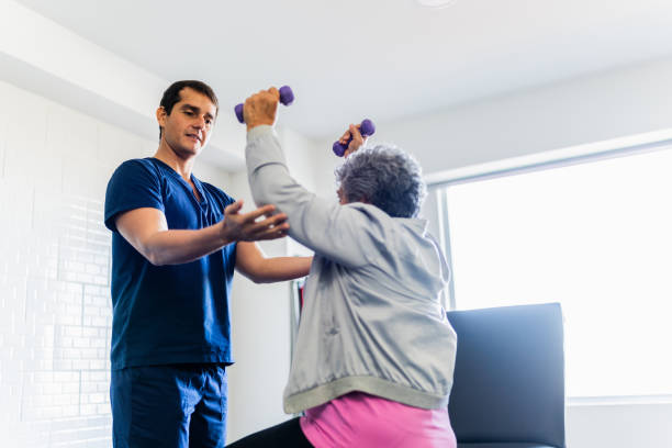 istock Mid adult physical therapist helping patient during exercise with dumbbell 2200807618