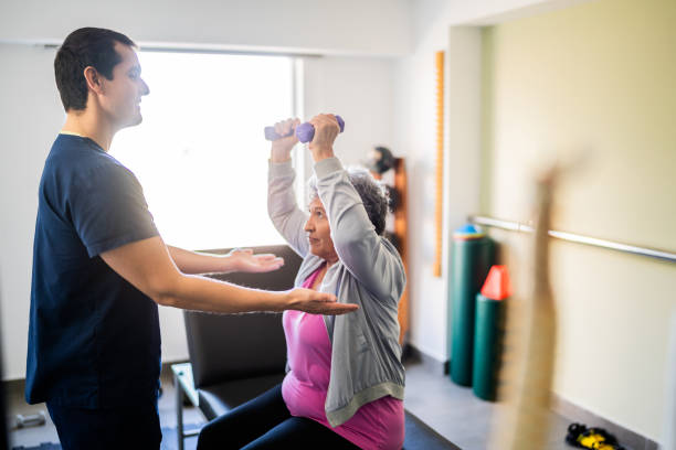 istock Mid adult physical therapist helping patient during exercise with dumbbell 2200807620