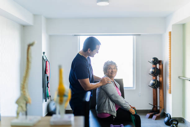 istock Mid adult physical therapist helping patient during exercise with elastic 2200807728