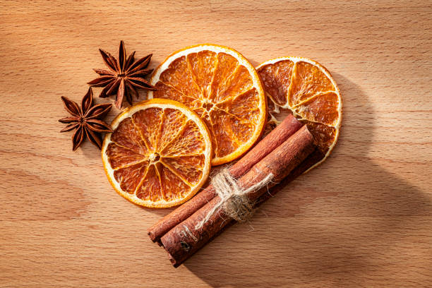 Scented dehydrated orange slices, star anise and cinnamon sticks shot from above on wood table
