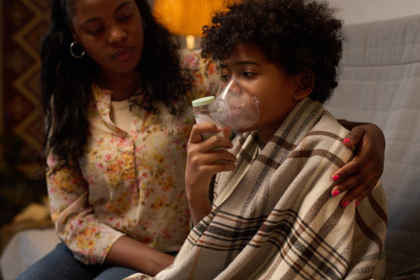 istock Comforting Child Using Inhaler Sitting on Sofa With Mother 2200812348