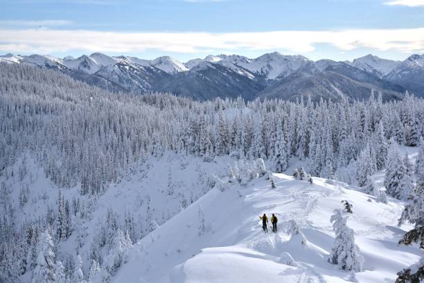 istock three people walking up a snow covered mountain side carrying snowboards 2200812763