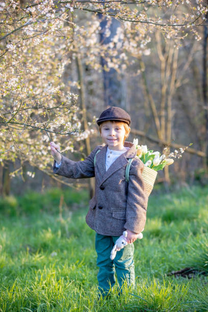 An Asian boy, about 4 years old, wearing a green T-shirt, was observing his flowers