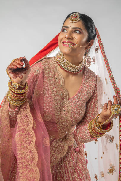 istock Smiling bride in pink wedding dress standing on white background 2200815428