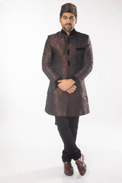 istock Confident groom in black kurta standing on white background 2200822974
