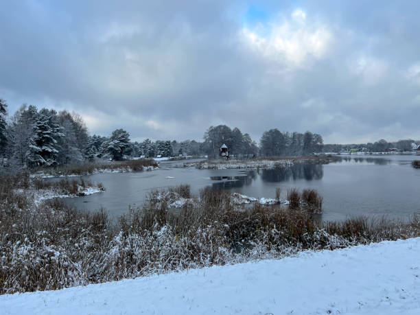 istock First snow and light frost over the pond with an island on which there is an old windmill, a tourist attraction 2200824749