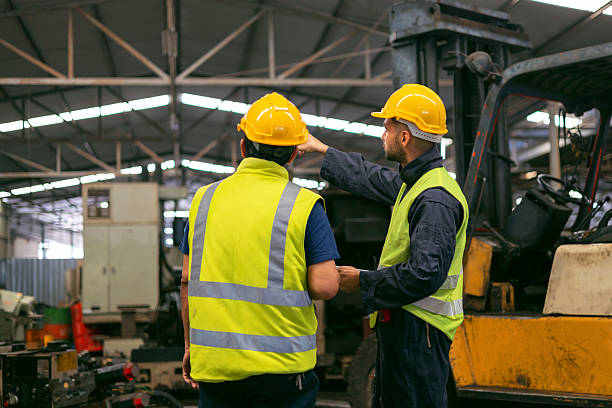 istock Two men in yellow safety vests are standing next to a forklift 2200827488