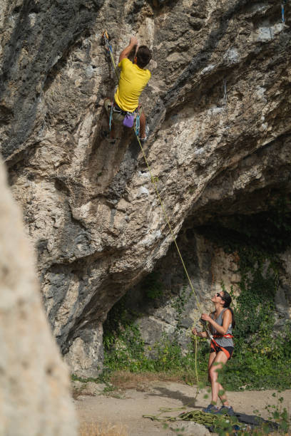 istock Climbing couple having exercises on a steep rocky cave. 2200828065