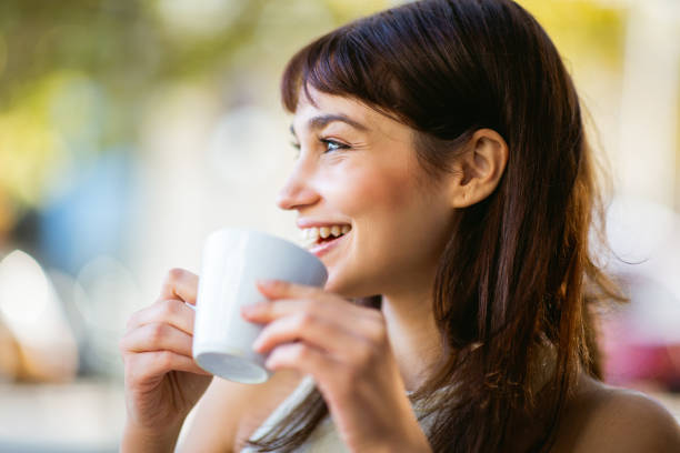 istock Smiling young woman drinking coffee at cafe 2200828372
