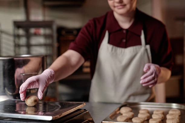 istock Female Chef in Gloves Scaling Round Shaped Dough while Baking Pastries Indoors 2200829775