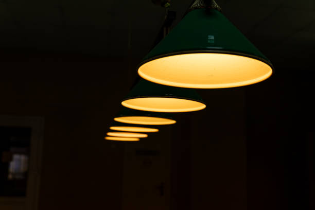 Pool table lit by lamps on a dark background. Low key shooting in low light.