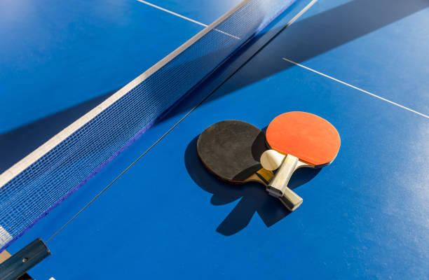 istock Dramatic studio shot of two professional-grade ping pong paddles featuring contrasting black and red rubber surfaces, wooden handles, and competition ball against backdrop 2200833847