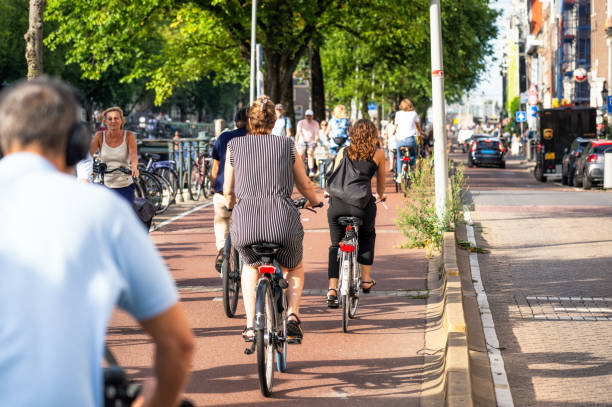 Amsterdam, Netherlands - People cycling on a segregated bicyle lane in central Amsterdam during sunny weather.