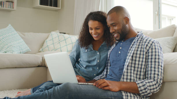 istock Young Couple Sitting On Floor In Lounge Using Laptop Together 2200845733