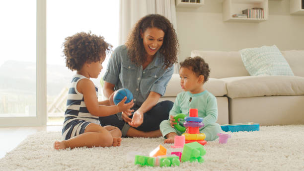 istock Mother Sits With Children At Home Playing With Plastic Stacking Toys 2200845830