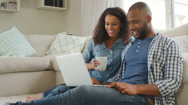 istock Young Couple Sitting On Floor In Lounge Using Laptop Together 2200846513
