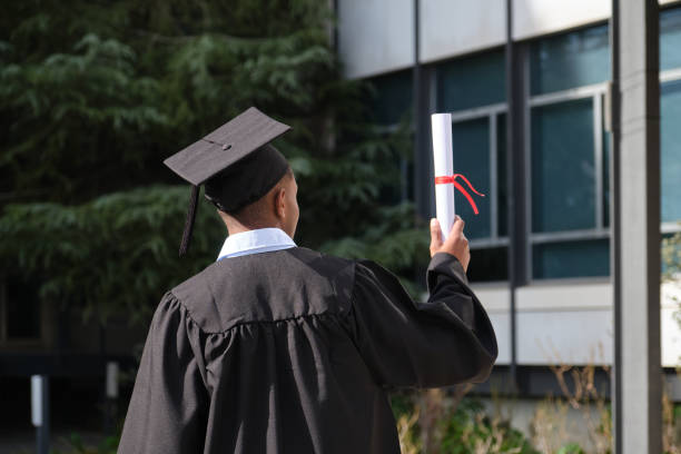 istock Graduate student holding diploma looking at university building 2200848315