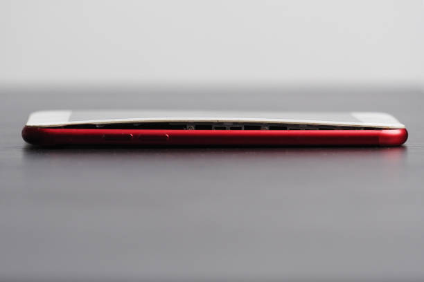 istock Red smartphone from the side with swollen battery. 2200848468