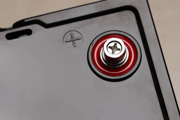 Close-up of black Lithium battery with red and black terminals positioned on a tiled surface indoors.