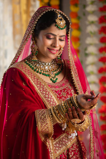 istock Bride in red dress looking at her bangles in wedding ceremony 2200848819