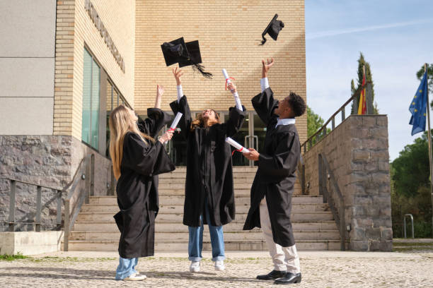 istock Happy graduating students throwing their graduation caps in the air 2200849628