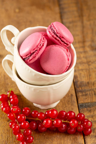 A close-up of colorful  pink strawberry macaroons, piled high in coffee cups.
