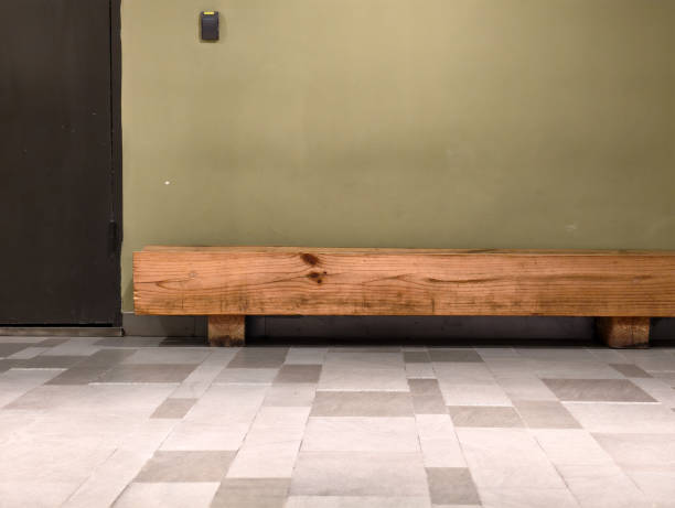 A close-up view of a row of traditional wooden benches with warm brown tones, suggesting an old church, waiting area, or assembly hall. The focus is on the rustic wood grain and repetitive pattern.