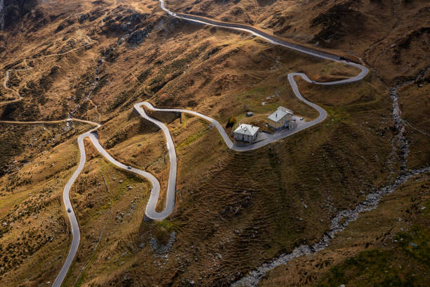 Aerial view of a mountain winding road and two buildings in the Swiss Alps.