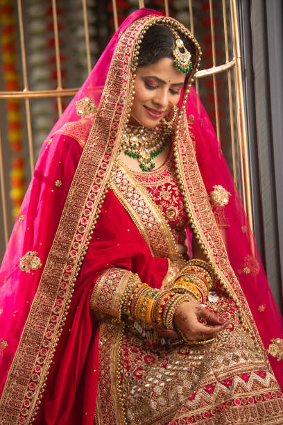 istock Bride in red dress looking at her bangles in wedding ceremony 2200860309