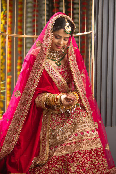 istock Bride in red dress looking at her bangles in wedding ceremony 2200860345