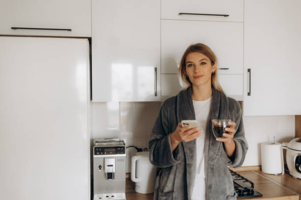 istock Young woman enjoying fresh aromatic coffee near modern machine in kitchen 2200864850