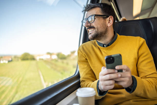 istock Smiling businessman using smartphone while traveling by train 2200867842