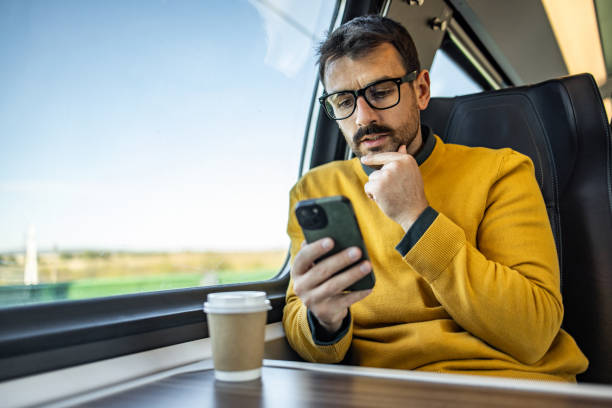 istock Smiling businessman using smartphone while traveling by train 2200867869