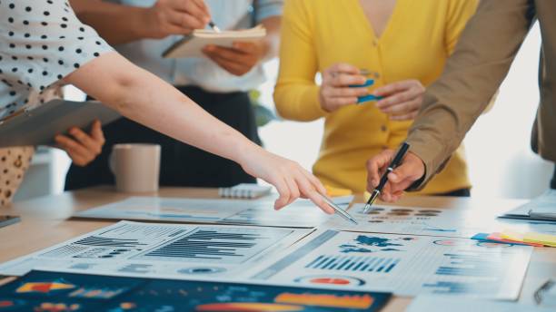 istock Collaborative Business Meeting with Charts, Graphs, and Notes on Table, Professionals Engaged in Discussion and Planning in Modern Office Environment SACTR 2200871976