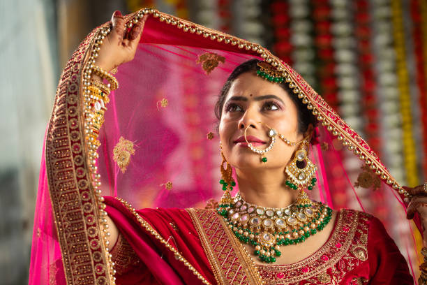 istock Beautiful bride with red veil on her head posing in wedding ceremony 2200874826