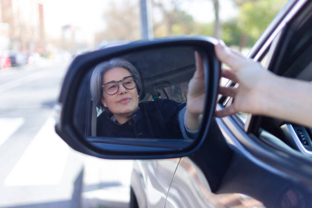 istock Mature woman adjusting side mirror while driving car in city 2200875214