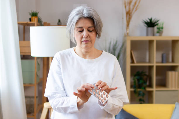 istock Senior woman taking medication from blister pack at home 2200875595